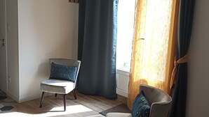 Une pièce avec deux chaises, une fenêtre avec des rideaux et un plancher en bois.