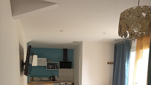 Une chambre moderne avec un grand lit, un bureau et, au fond, un coin cuisine.
