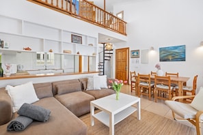 A living room with a sofa, coffee table, and dining area with chairs and a table.