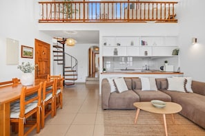 A modern interior with a dining area, a sofa set, a staircase, and a kitchen. - Tramontana 115-P1 - Caressing the Mediterranean (Fornells)