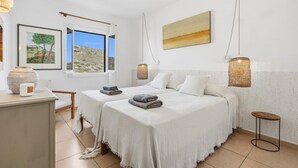 Une chambre d’hôtel avec deux lits, une grande fenêtre, un tableau et une petite table.