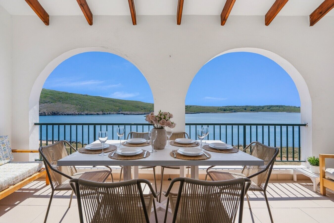 A dining table set for four with a view of a lake and hills.