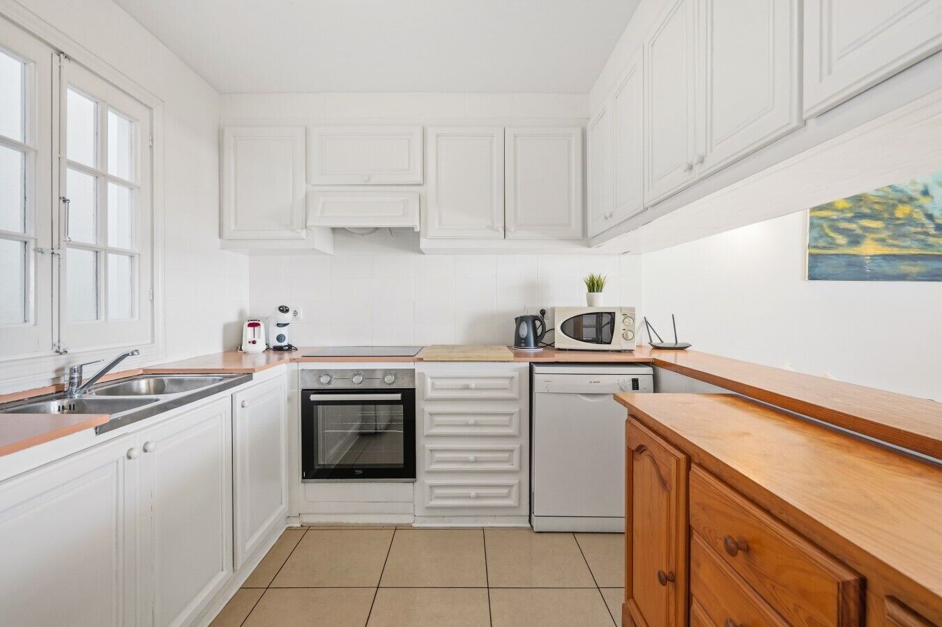 A compact kitchen with white cabinetry, a built-in oven, a microwave, and a dishwasher.