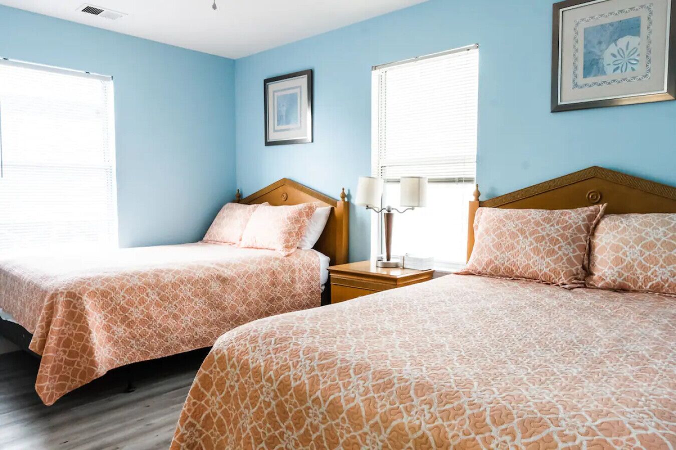 Een hotelkamer met twee bedden, een nachtkastje en een raam met jaloezieën.