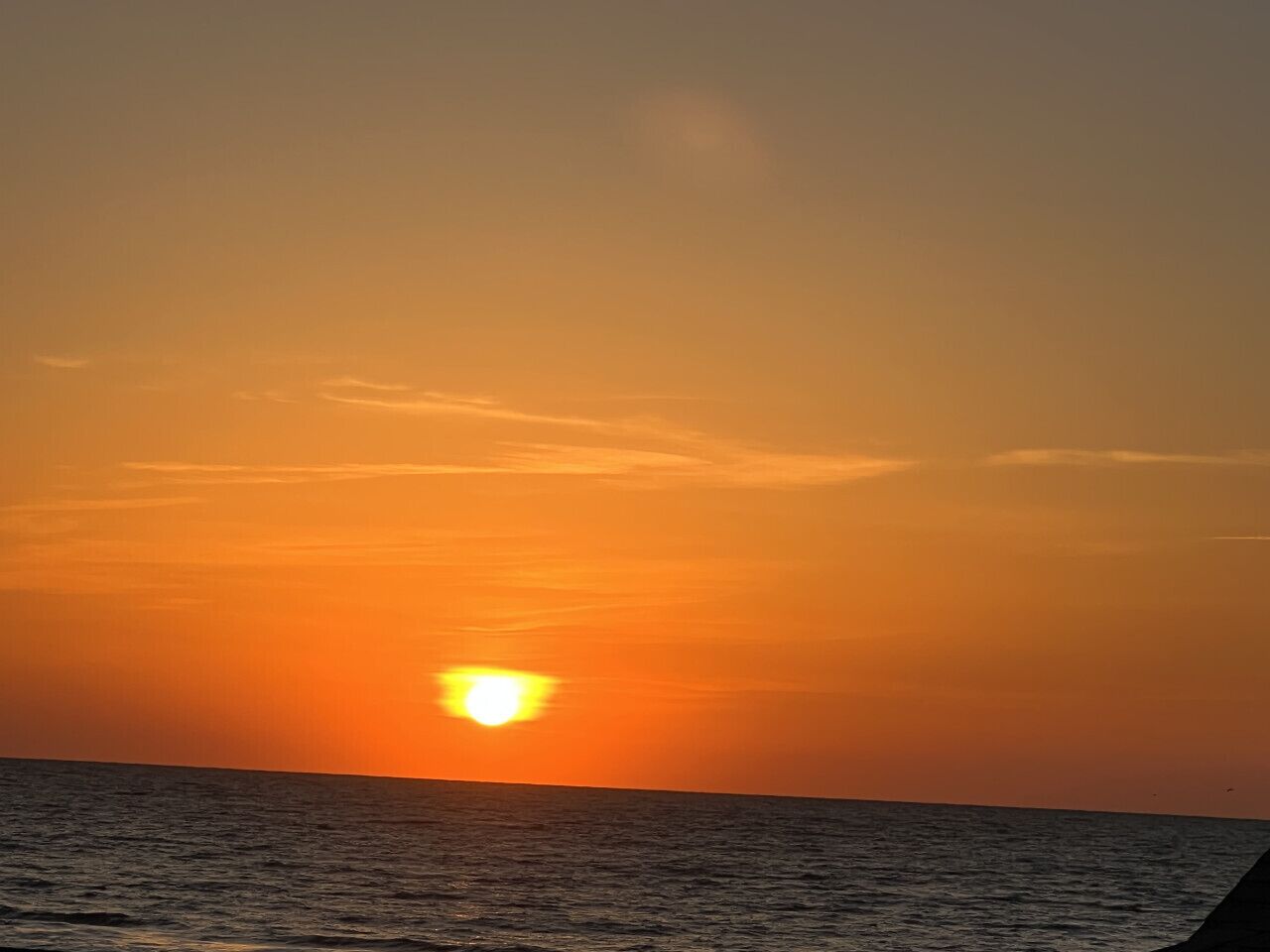 A sunset over the ocean with a clear sky.
