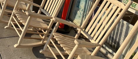 A row of wooden rocking chairs lined up outside a building with a sign that reads "Cottage House."