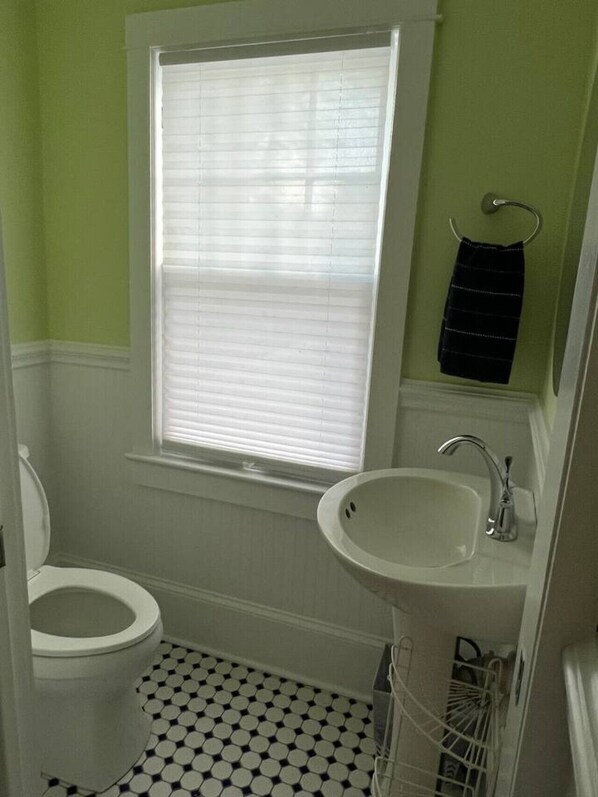 A bathroom with a toilet, sink, and window with blinds.