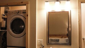 Ein kleines Badezimmer mit Waschmaschine, Waschbecken und Spiegel.