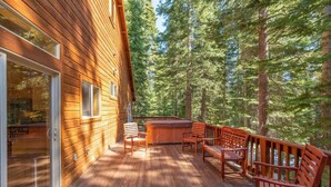 A wooden deck with a hot tub and seating area surrounded by trees. - Everything You Need in a Mountain Cabin (Truckee)