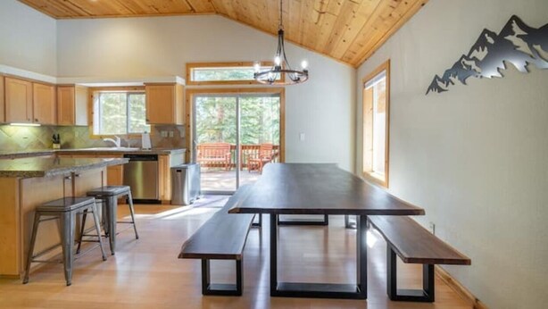 A spacious kitchen with wooden cabinets, a large dining table, and bar stools. - Everything You Need in a Mountain Cabin (Truckee)