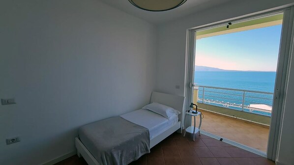 Una habitación pequeña con cama individual y balcón con vistas al mar.