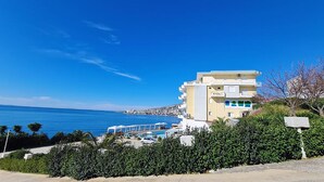A coastal building with a pool, surrounded by greenery and overlooking the sea. - Planet Apartments (Sarandë)