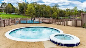 A swimming pool with a wooden deck and a hot tub, surrounded by a fence and trees. - GolfView Chalet at the Woods Resort, Central Air and Heat (Hedgesville)