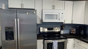 A modern kitchen with stainless steel appliances, including a refrigerator, microwave, and oven. - The Snapper House-Carrabelle (Carrabelle)