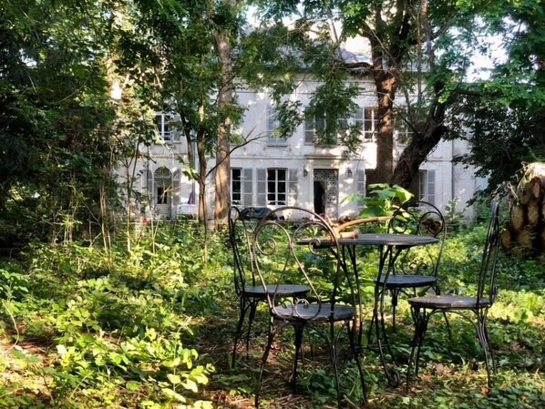 A garden with a table and chairs, surrounded by lush greenery and a large tree. - YXIE - Manoir des Arts (Villeblevin)