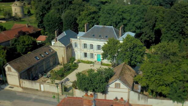 A model of a residential area with a prominent house featuring a large front porch, a garage, and a small detached building.