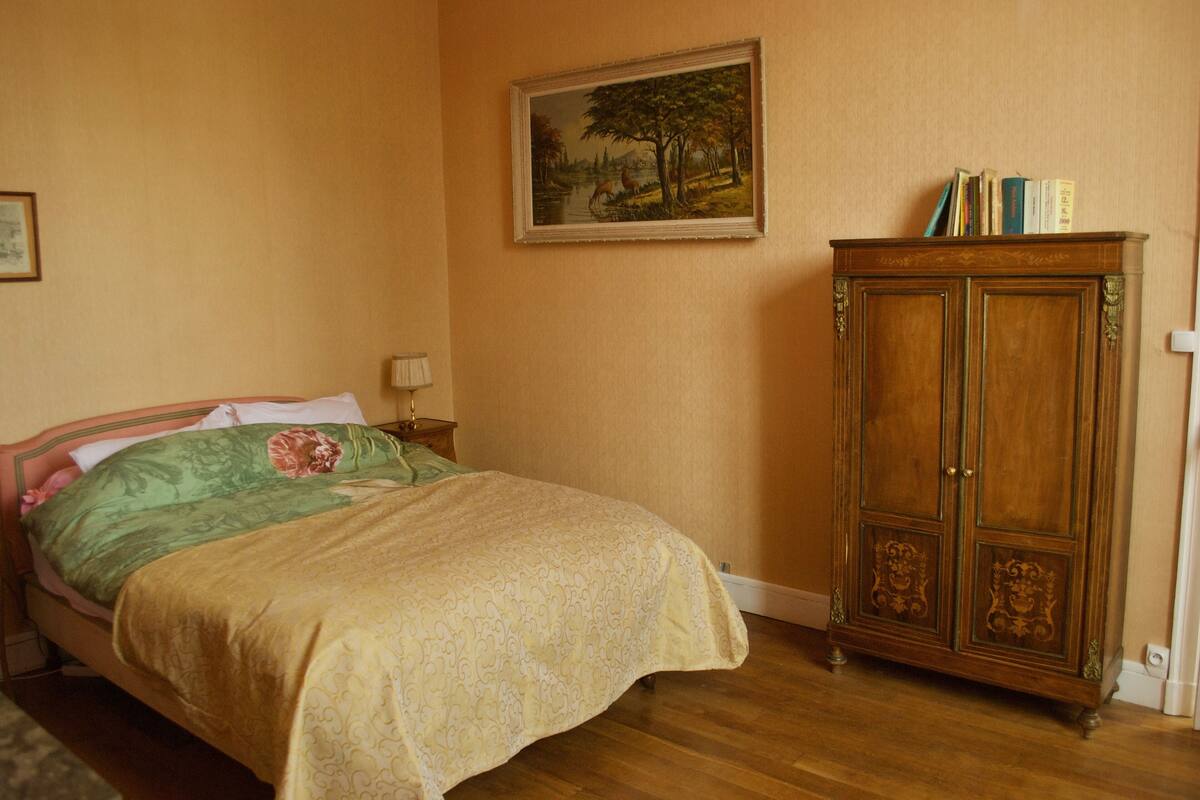 Un dormitorio con una cama, un armario de madera y un cuadro en la pared.