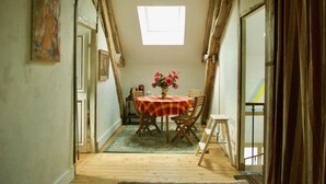 A narrow room with a wooden floor, a table with a checkered tablecloth, and a vase with flowers.