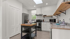 A modern kitchen with white cabinets, a black countertop, and a wooden table. - Physician`s Loft in the heart of downtown with 2 Free Parking Spots (Bar Harbor)