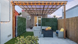 A covered patio with a fire table, outdoor seating, and a wooden fence. - 3blocks2beach, Free Parking, A/C, Fast Wifi (San Diego)
