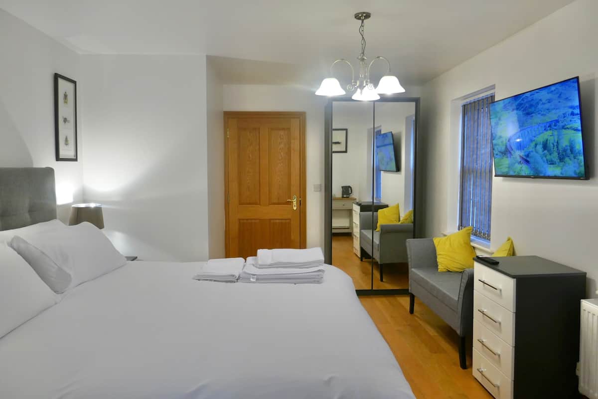 Ein Hotelzimmer mit Bett, Schreibtisch, Stuhl und Fernseher.
