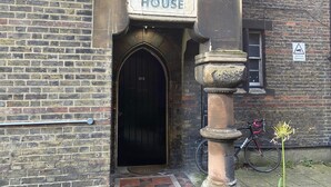 Ein Backsteinhaus mit einem Schild, auf dem "HERBERT HOUSE" über einem dunklen, bogenförmigen Eingang steht.