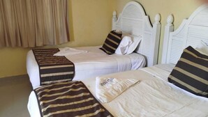 A room with two single beds, each with striped bedding and pillows.