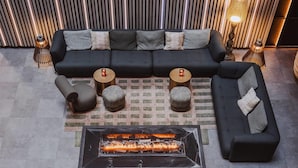 Un espace extérieur moderne aménagé avec un foyer, des canapés et des tables rondes.