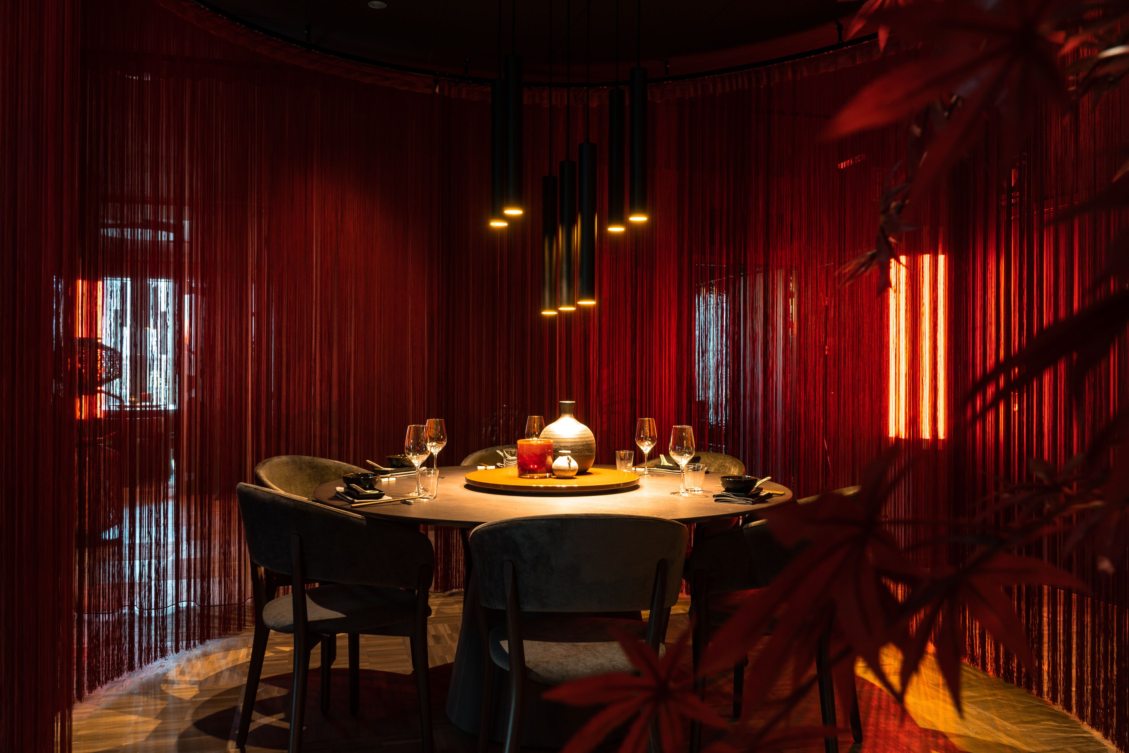 Une salle à manger à la lumière tamisée, avec une table ronde, des chaises et un luminaire central.