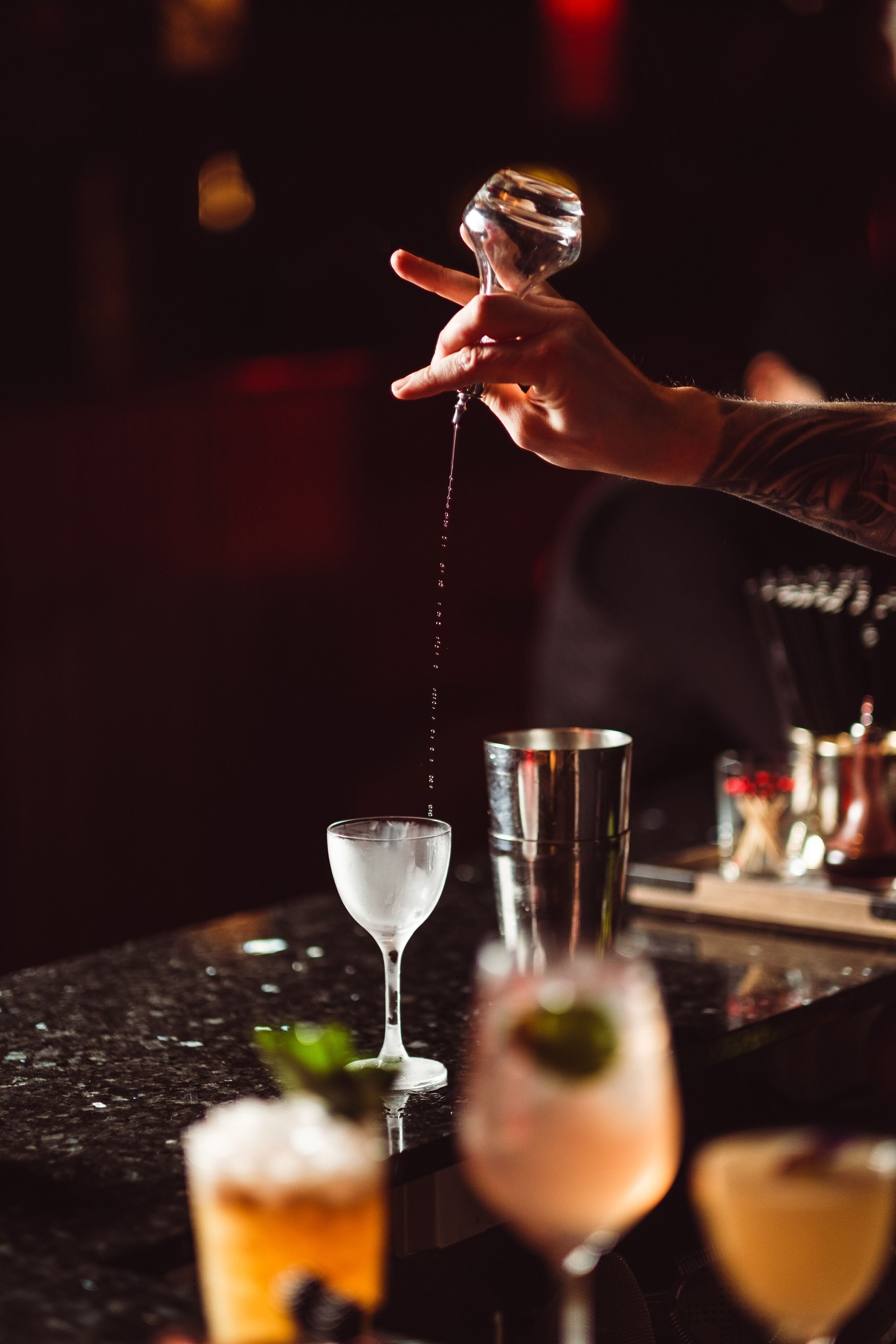 A bartender pouring a drink into a glass.