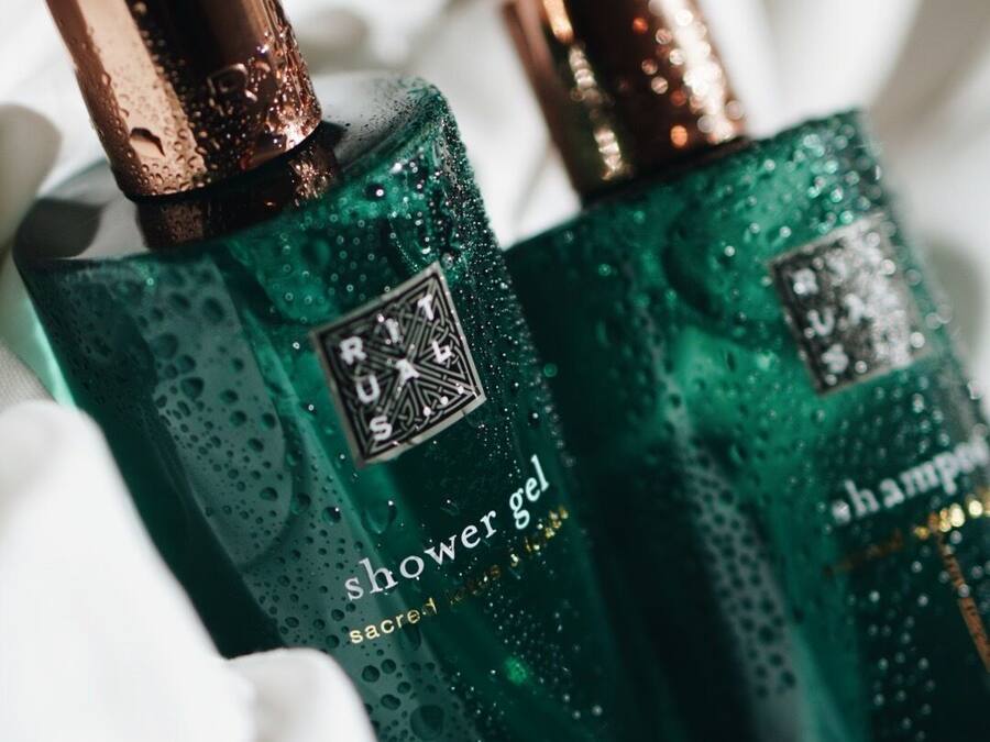 Two bottles of shower gel with pumps, placed on a white fabric surface.