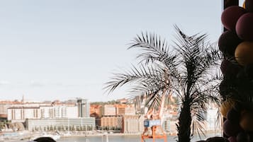 A group of people seated at a table with a view of a harbor and buildings in the background.