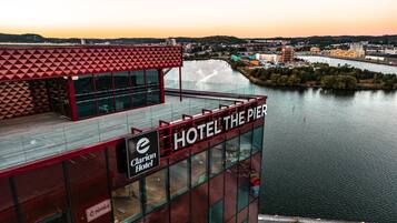 Un hotel con un letrero llamativo que dice "HOTEL THE PIER" y "Clarion Hotel", en un edificio moderno con grandes ventanales con vista a un cuerpo de agua.