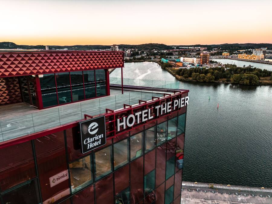 A hotel with a prominent sign reading "HOTEL THE PIER" and "Clarion Hotel" on a modern building with large windows overlooking a body of water.