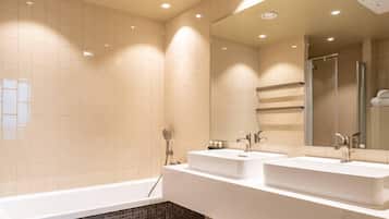 A modern bathroom with two sinks, a bathtub, and a shower.