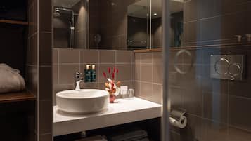 A modern bathroom with a large sink, mirror, and glass shower enclosure.