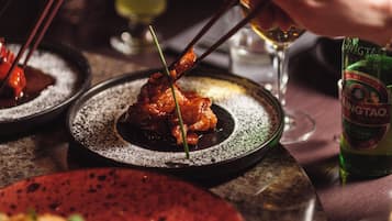 Una mesa de comedor con platos de comida, palillos y una botella de cerveza.