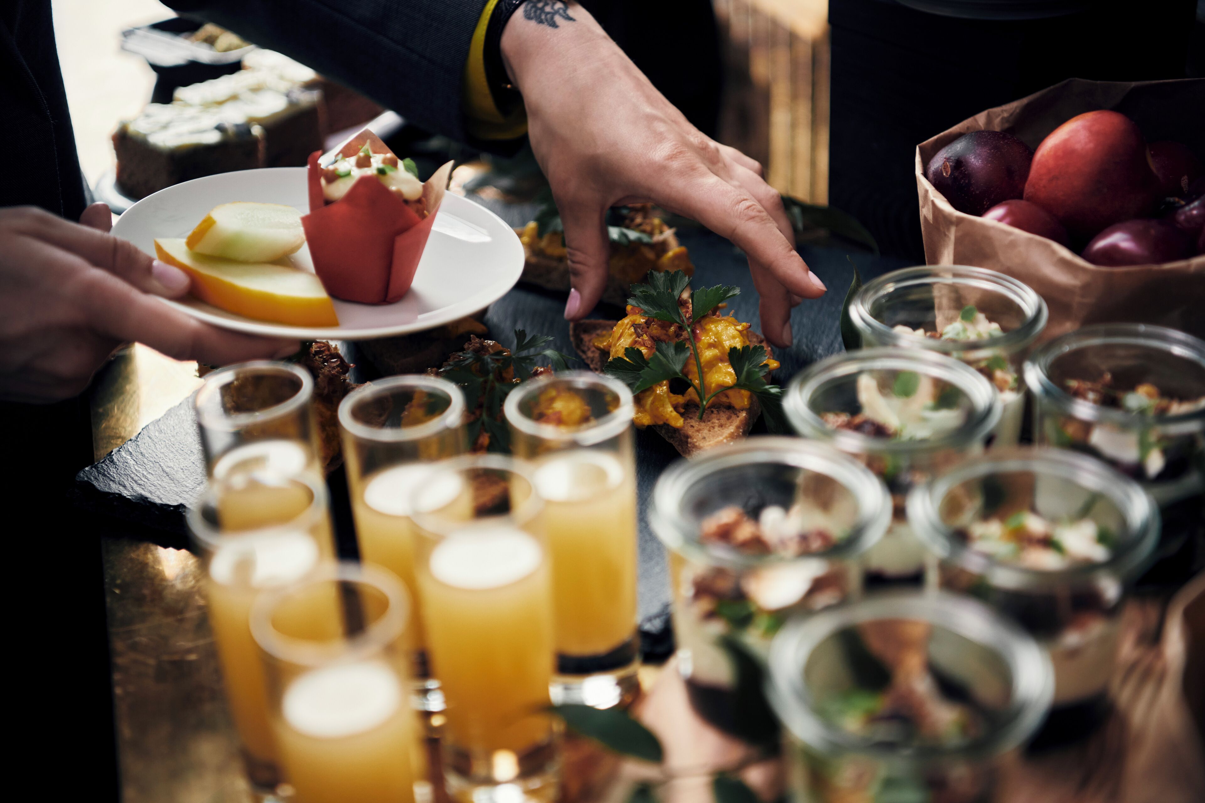 A table with various food items and drinks, including a plate with a cupcake and a bowl of fruit.