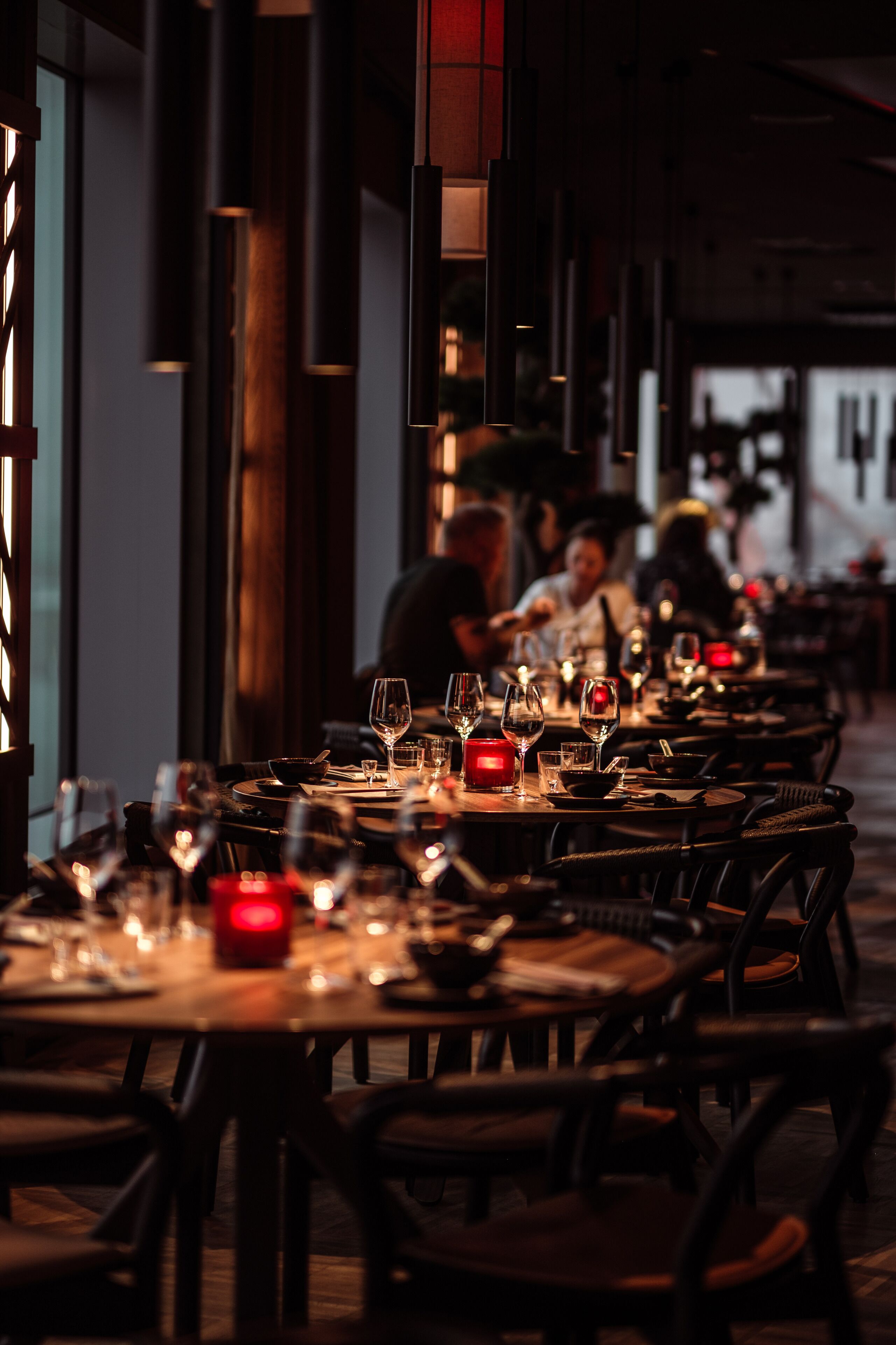 En restaurang med flera bord dukade för middag, med ljus och vinglas.