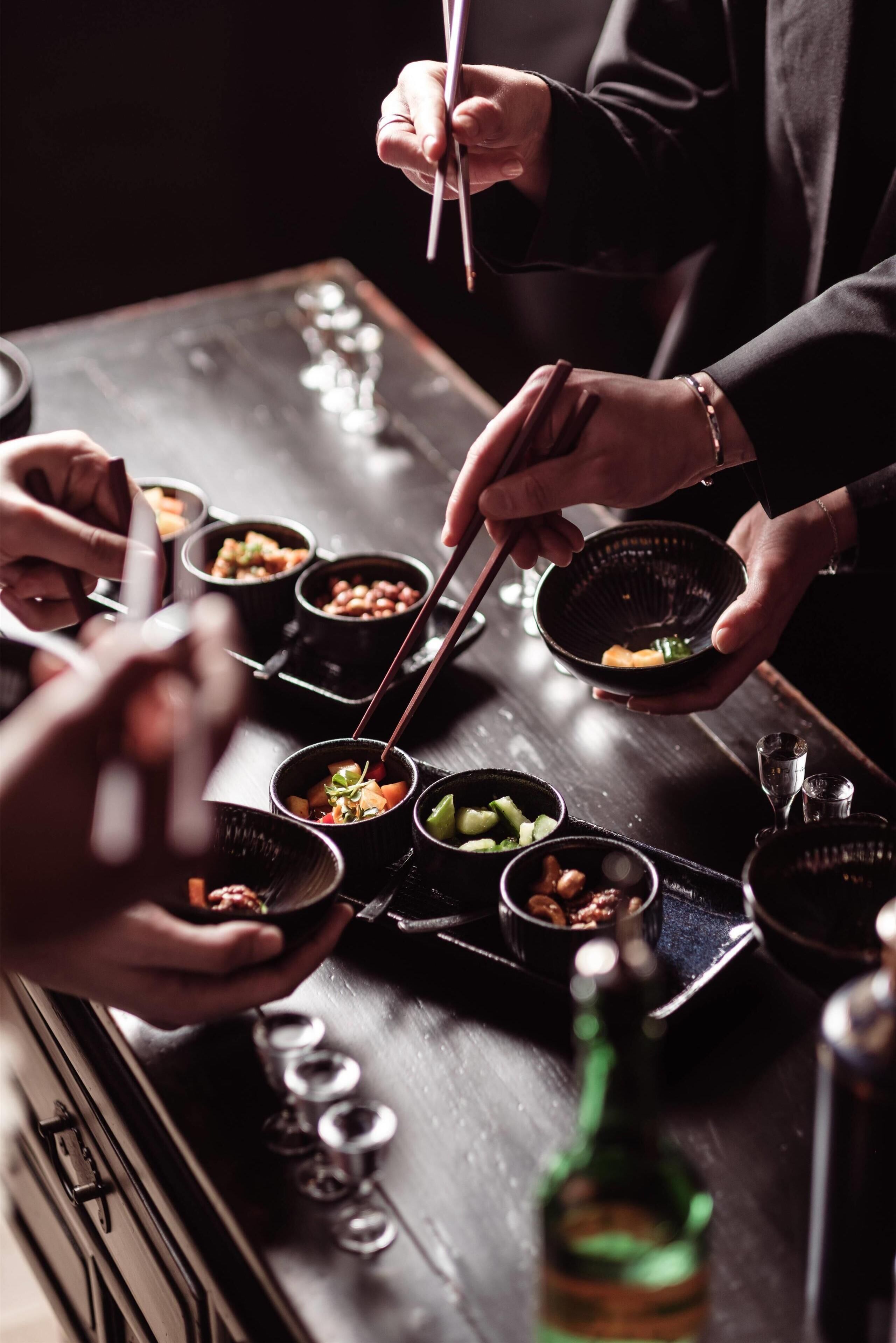 A person serving food from small bowls on a tray.