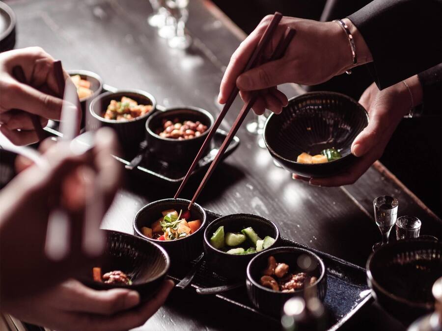A person serving food from small bowls on a tray.