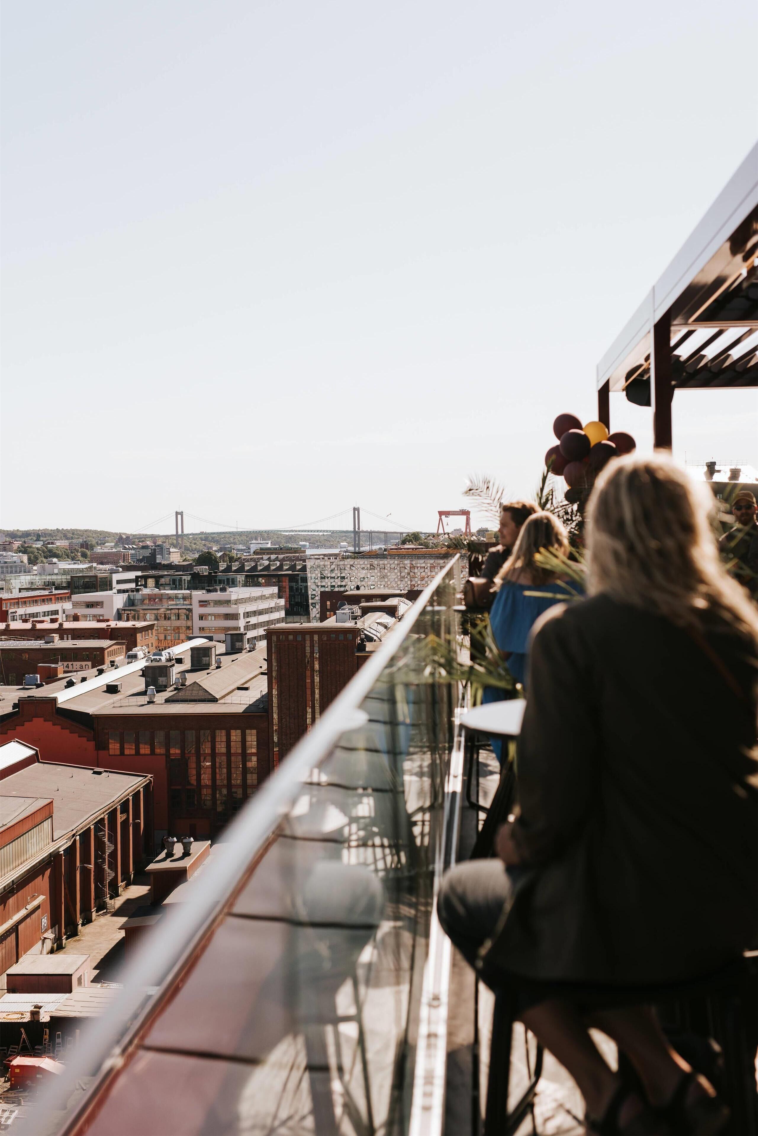 A rooftop terrace with a clear view of the cityscape, including buildings and a bridge.