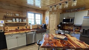 A spacious kitchen with wooden cabinets, a large island, and modern appliances. - Newly built LOG Cabin-Float, Golf, Hike, Hunt, Fish, visit a winery...Relax! (cuba)