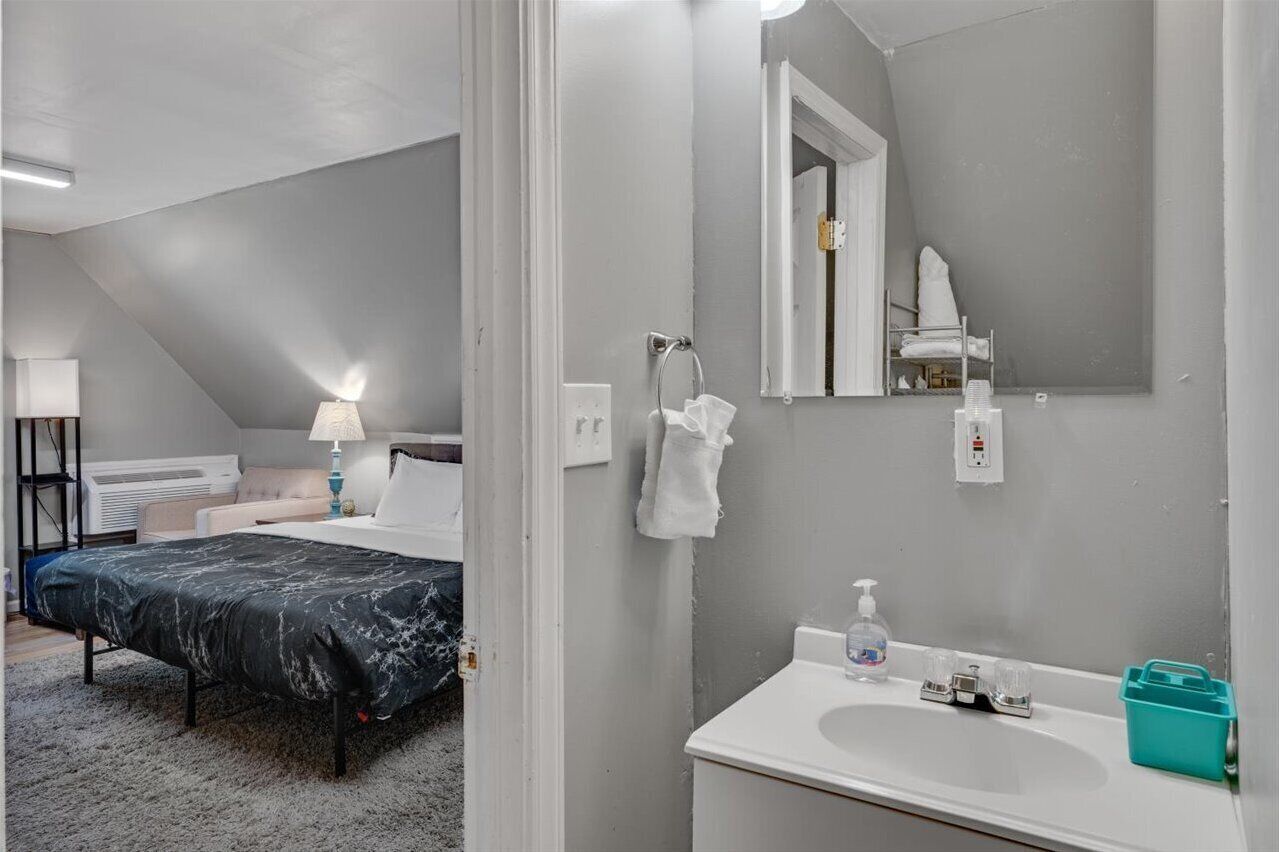 Une chambre à coucher avec un lit, une table de chevet, une lampe et une vue sur la salle de bain.
