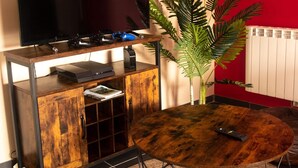 A living room with a flat-screen TV, gaming console, and a coffee table with a plant. - Cosy 2-bedroom Apartment in the Center of Hotton (Hotton)