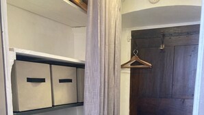 Un armario con estantes y espacio para colgar, una puerta de madera y un suelo de tono claro.