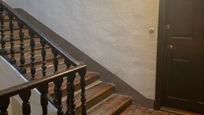 Una escalera de madera con barandilla que lleva a una puerta de madera oscura.