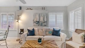 A living room with a white sofa, a wooden coffee table, and a ceiling fan. - Key Lime Cottage - Updated - 1 Minute Walk to Beach & Pier (Flagler Beach)