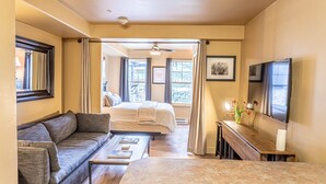 Hotelkamer met een bank, een bed, een eettafel, een televisie en uitzicht op de omgeving.