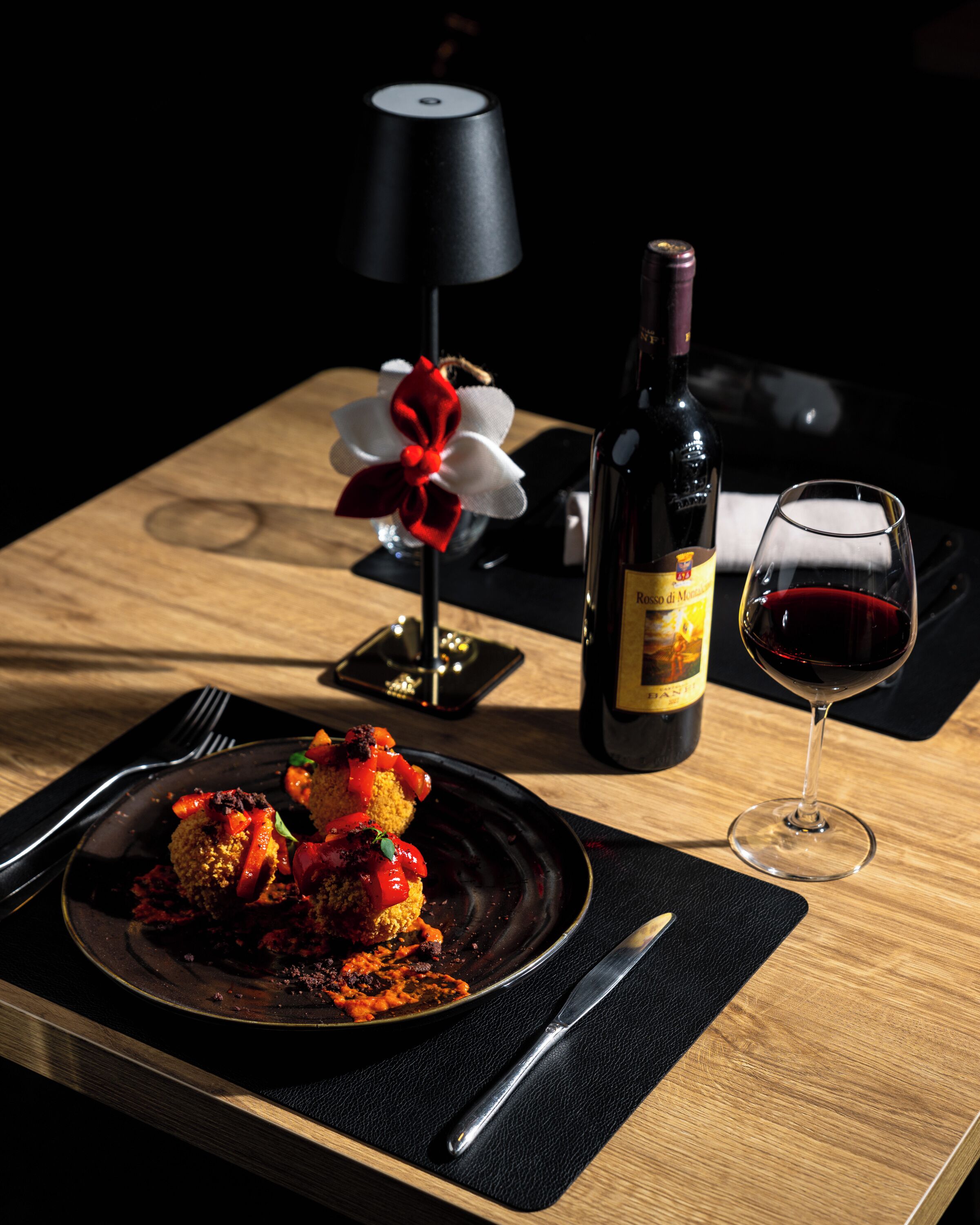 A dining table with a plate of food, a wine bottle, and a wine glass.